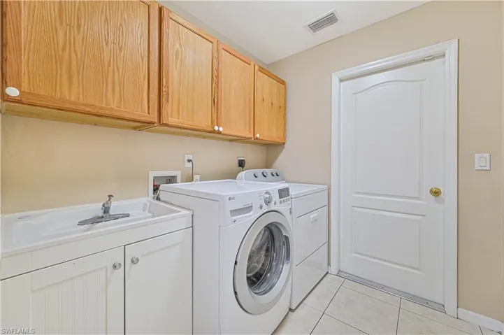 Washroom featuring cabinets, washer and dryer, sink, and light tile patterned floors