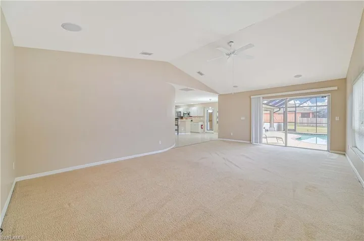 Unfurnished living room featuring light carpet, lofted ceiling, and ceiling fan