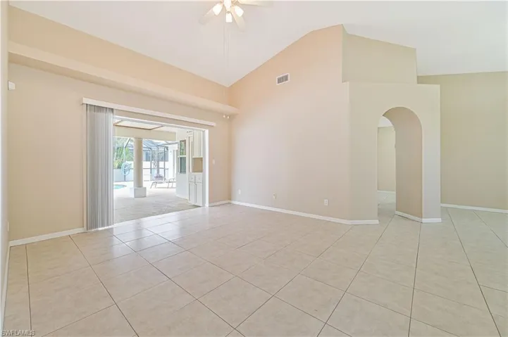 Tiled spare room with high vaulted ceiling and ceiling fan