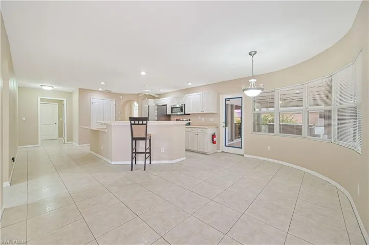Kitchen featuring light tile patterned flooring, hanging light fixtures, a center island, appliances with stainless steel finishes, and a kitchen breakfast bar