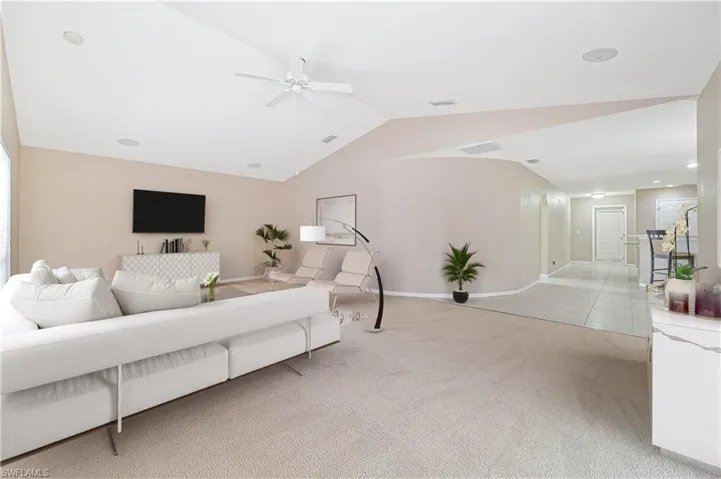 Carpeted living room featuring ceiling fan and lofted ceiling
