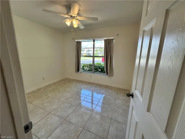 Empty room with light tile patterned floors, a ceiling fan, and a textured ceiling