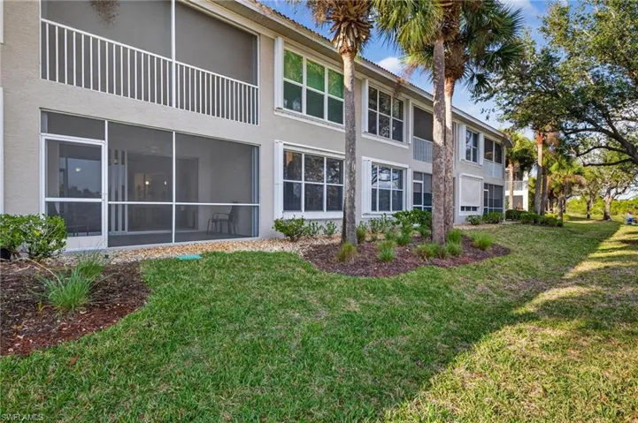 Back of property with stucco siding, a lawn, and a sunroom
