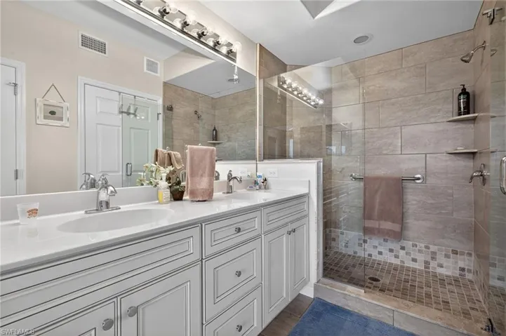 Full bathroom with double vanity and a shower stall
