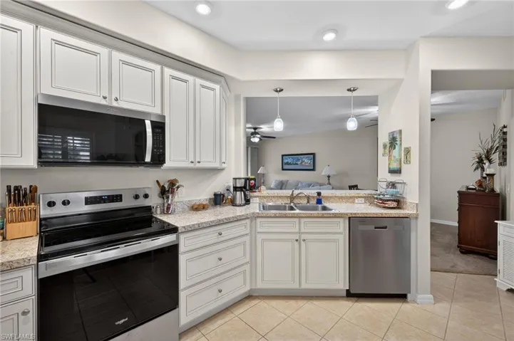 Kitchen featuring stainless steel appliances, hanging light fixtures, white cabinetry, open floor plan, and a ceiling fan