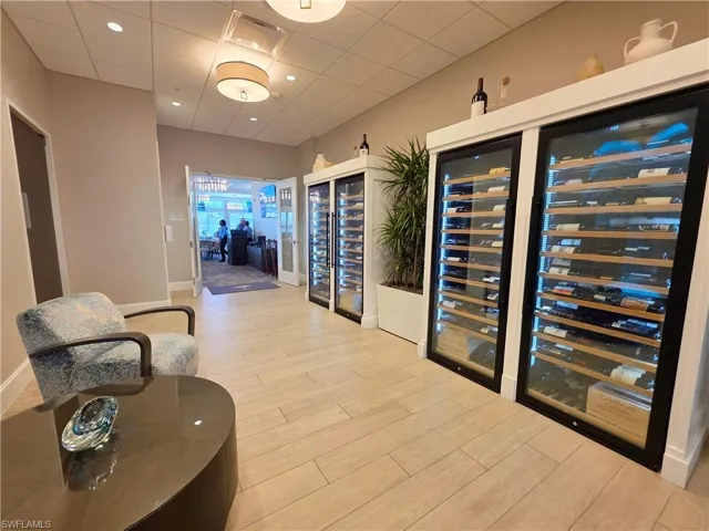 Wine area with wine cooler, light wood-type flooring, a drop ceiling, and recessed lighting