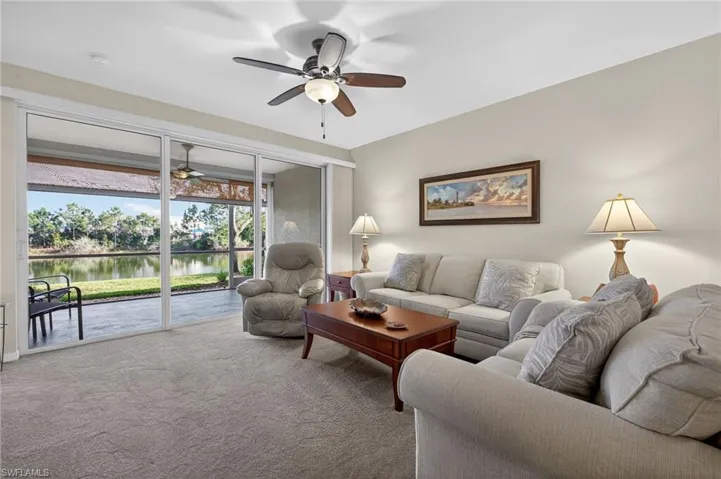 Living room with ceiling fan, a water view, and carpet