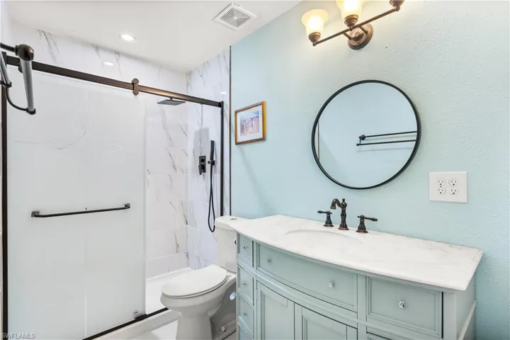 14939-Full bathroom featuring vanity, bath / shower combo with glass door, and toilet