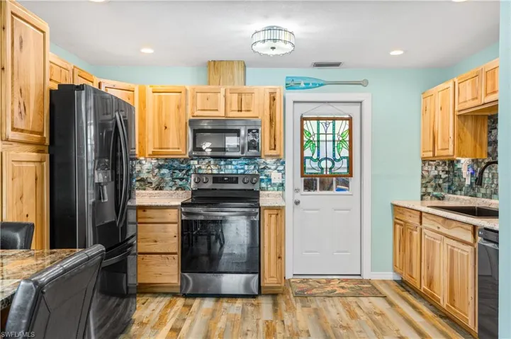 14937-Kitchen featuring black appliances, tasteful backsplash, sink, light stone counters