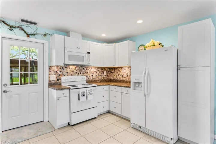 14939-Kitchen featuring white cabinets, tasteful backsplash, white appliances