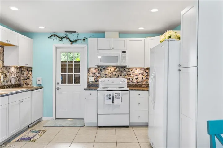14939-Kitchen with light tile patterned floors, backsplash, white appliances, and sink