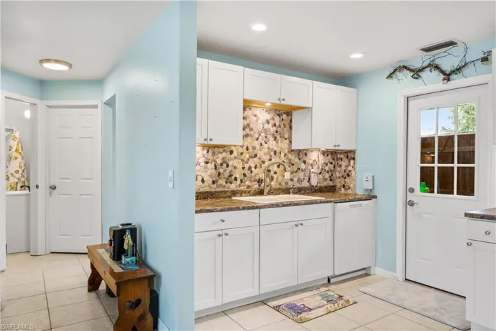 14939-Kitchen featuring light tile white cabinets, white dishwasher, decorative backsplash, and sink