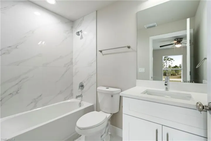 Contemporary bathroom featuring a white vanity with an integrated sink, a large mirror, and a full-size bathtub with a wall-mounted showerhead