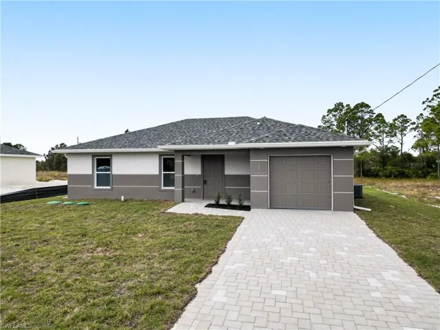 Contemporary single-story residence featuring a two-tone exterior, a gray shingle roof, an integrated single-car garage, and a light-colored paver driveway