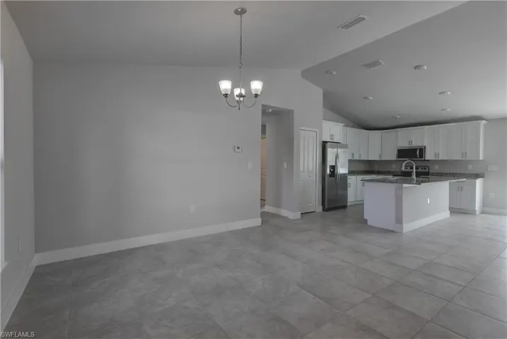 Kitchen featuring light tile patterned flooring, an inviting chandelier, stainless steel appliances, and a center island with sink