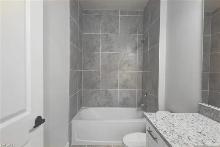 Full bathroom featuring toilet, vanity, and tiled shower / bath