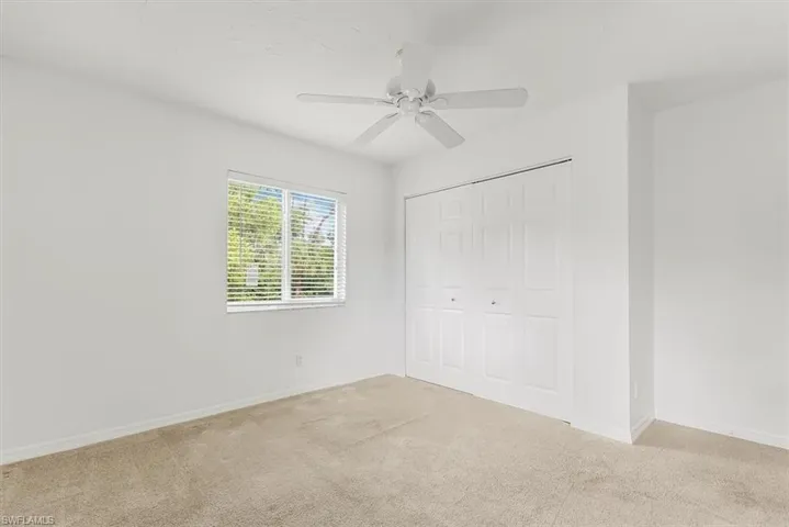 Unfurnished bedroom with carpet, a closet, and a ceiling fan