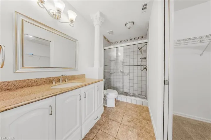 Full bath featuring vanity, a stall shower, light tile patterned flooring, and a spacious closet