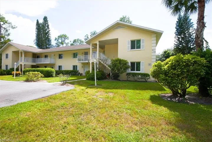 View of front of property featuring a front yard, stucco siding, and stairs