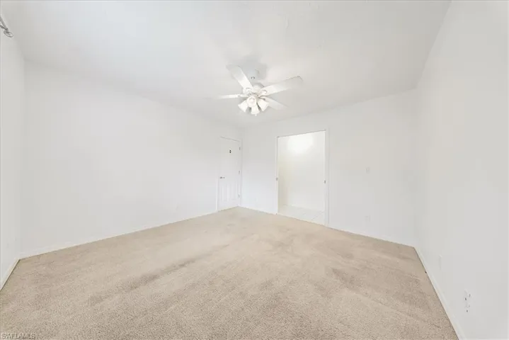 Empty room featuring light colored carpet and a ceiling fan