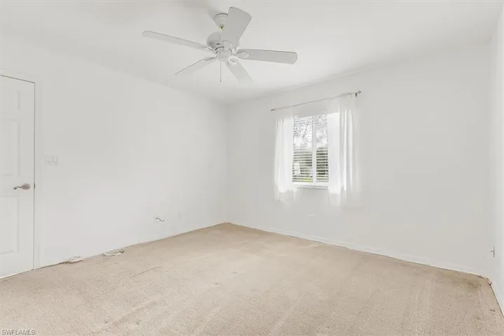 Unfurnished room featuring light carpet and a ceiling fan