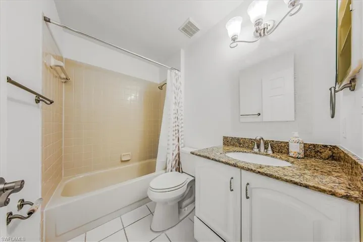 Full bathroom featuring tile patterned flooring, shower / bath combination with curtain, and vanity