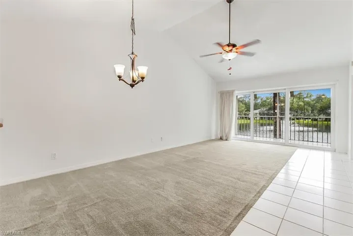 Unfurnished room featuring light carpet, ceiling fan, high vaulted ceiling, light tile patterned floors, and a chandelier