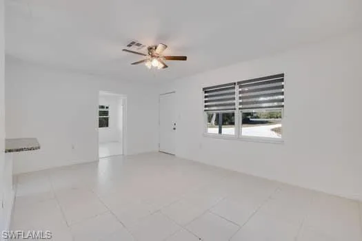 Empty room with ceiling fan and light tile patterned floors