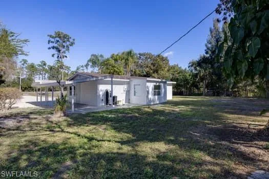 Rear view of house with a lawn, a patio area, and a carport
