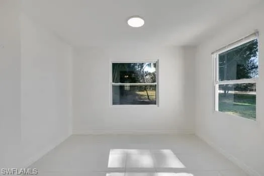 Spare room with light tile patterned flooring and baseboards