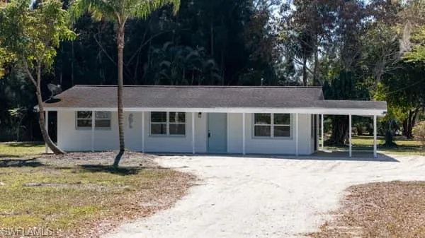 Ranch-style home with dirt driveway, a carport, and covered porch