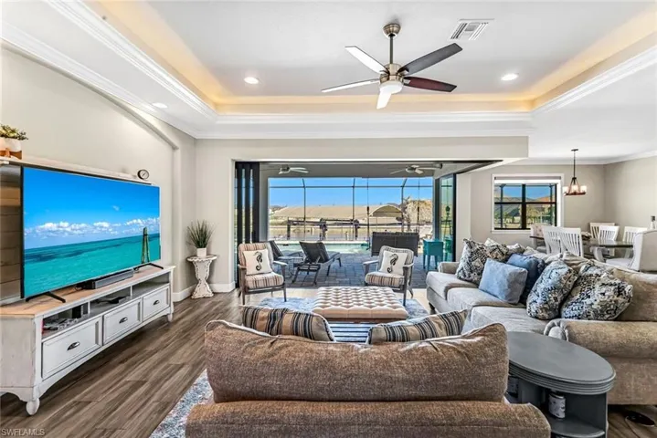 Great Room featuring dark hardwood/wood style floors, a raised ceiling ornamental molding with fan.