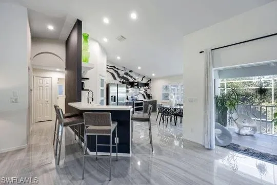 Kitchen with a kitchen bar, kitchen peninsula, stainless steel fridge with ice dispenser, and sink