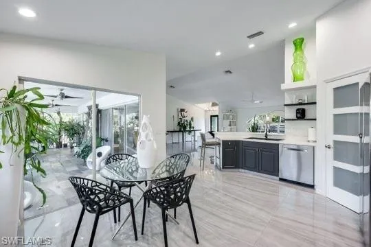 Dining room featuring french doors, ceiling fan, sink, and vaulted ceiling