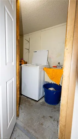 Laundry area with a textured ceiling and washer / dryer