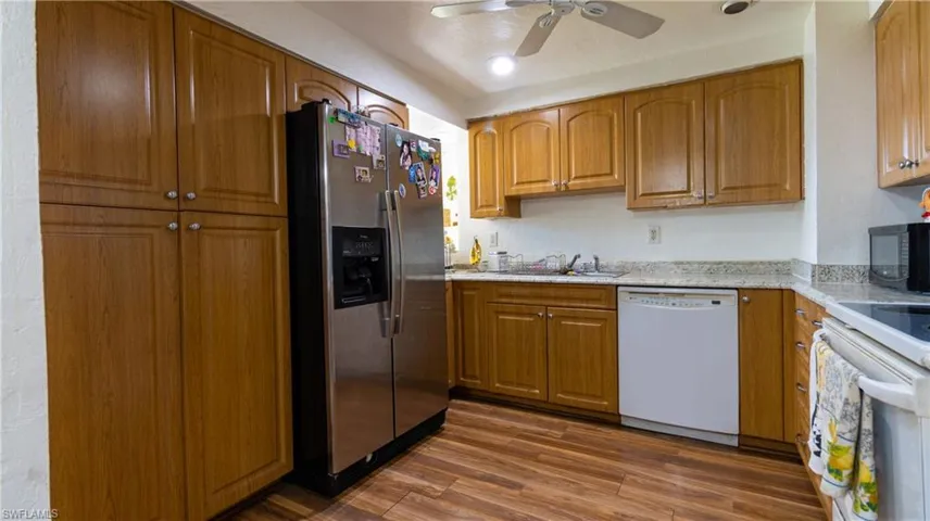 Kitchen with ceiling fan, dark hardwood / wood-style flooring, sink, and white appliances
