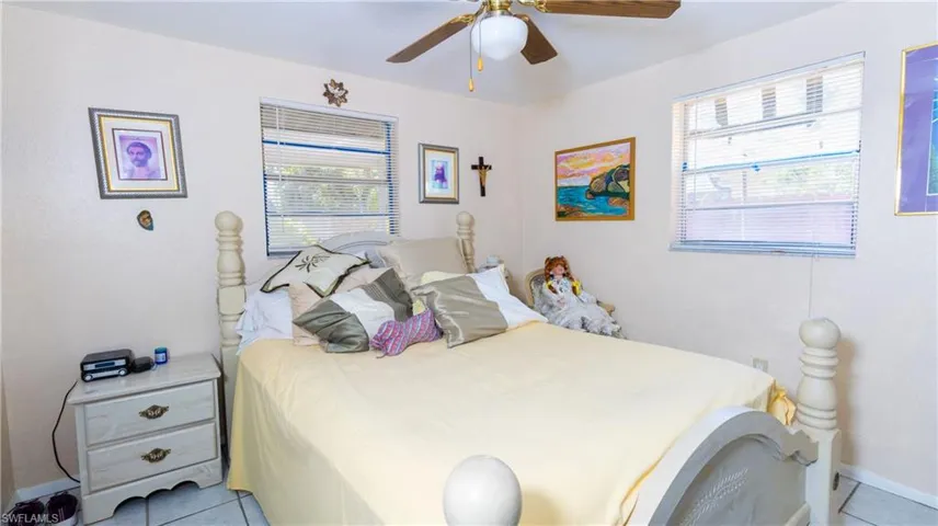 Bedroom with ceiling fan and light tile flooring