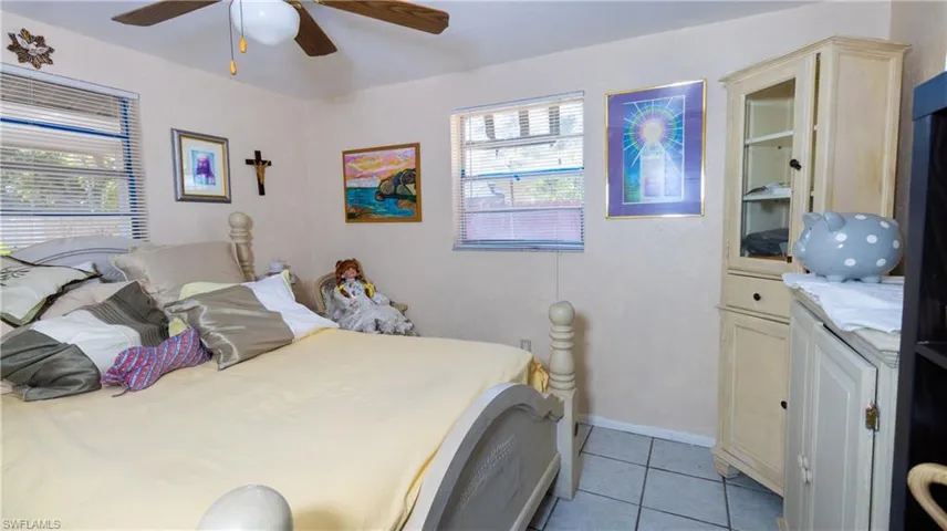 Tiled bedroom featuring ceiling fan and multiple windows