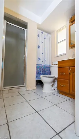 Bathroom with tile flooring, an enclosed shower, toilet, and vanity