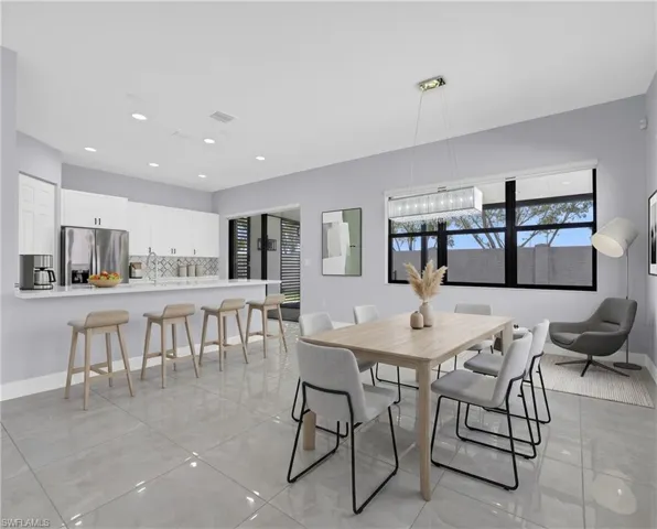 Virtually Staged Spacious kitchen and dining area featuring light gray tile flooring, recessed lighting, and a contemporary linear chandelier