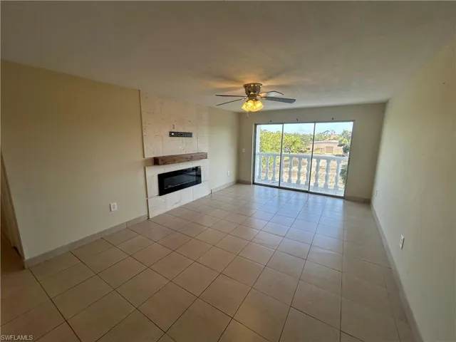 Unfurnished living room with a fireplace, ceiling fan, and light tile patterned flooring