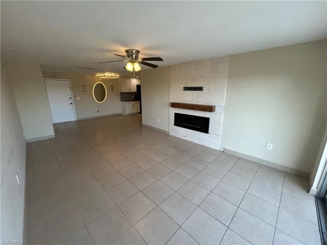 Unfurnished living room with ceiling fan, light tile patterned floors, and a fireplace