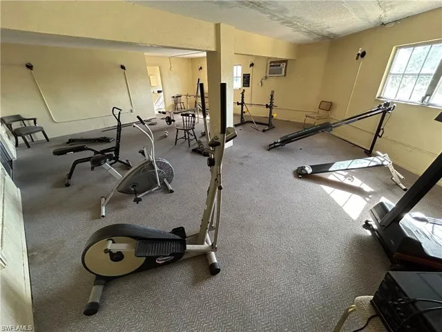 Workout area featuring a textured ceiling, carpet flooring, and a wall unit AC