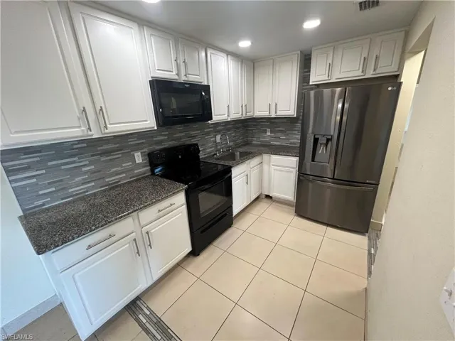 Kitchen featuring backsplash, white cabinetry, and black appliances
