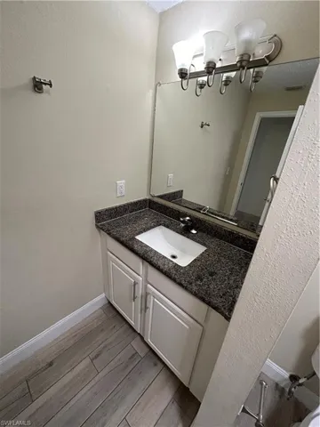 Bathroom with a notable chandelier, vanity, and wood-type flooring