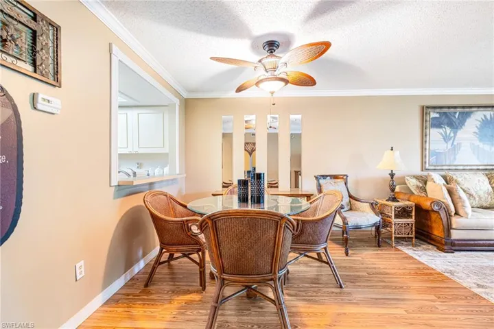 Dining room featuring a textured ceiling, light wood finished floors, ornamental molding, and ceiling fan