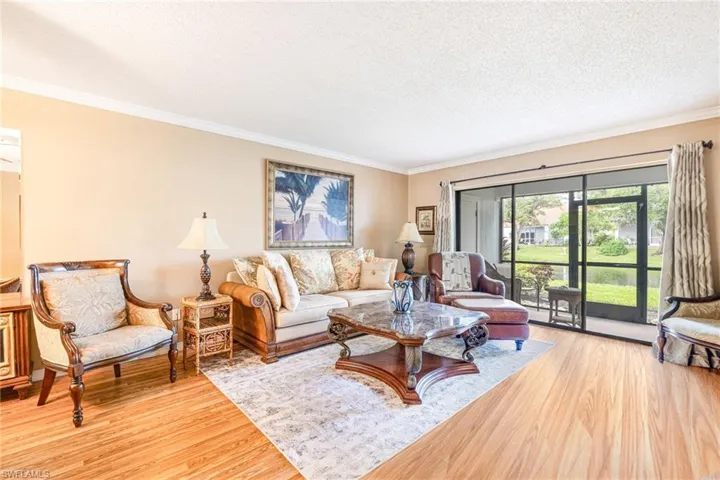 Living room with ornamental molding, light wood finished floors, and a textured ceiling