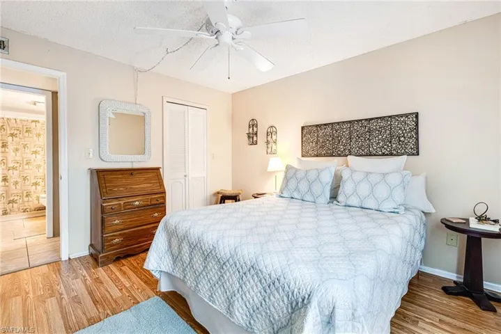 Bedroom featuring a textured ceiling, light wood finished floors, a closet, and a ceiling fan
