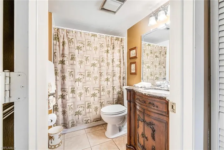 Bathroom with light tile patterned floors, vanity, and a shower with curtain
