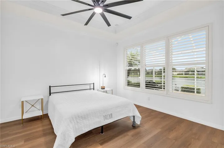 Bedroom with a tray ceiling, ornamental molding, dark hardwood / wood-style floors, and ceiling fan